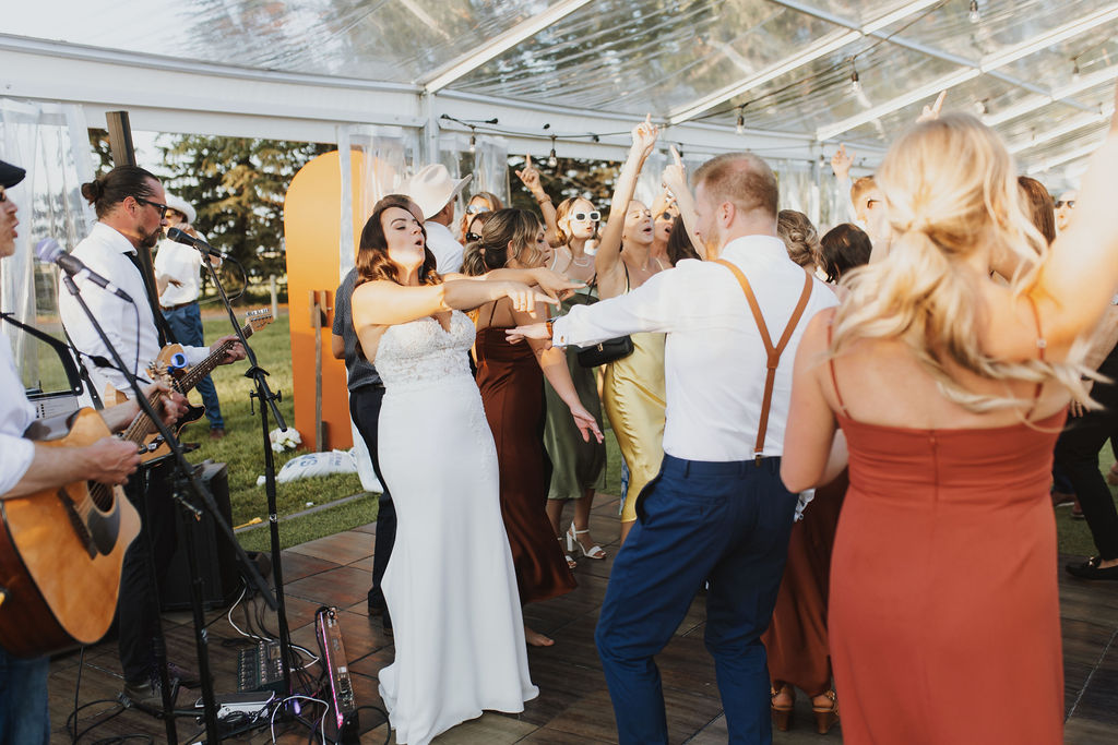 A group of people dancing on the dance floor at a Enchanting Outdoor Dinner Party wedding. 