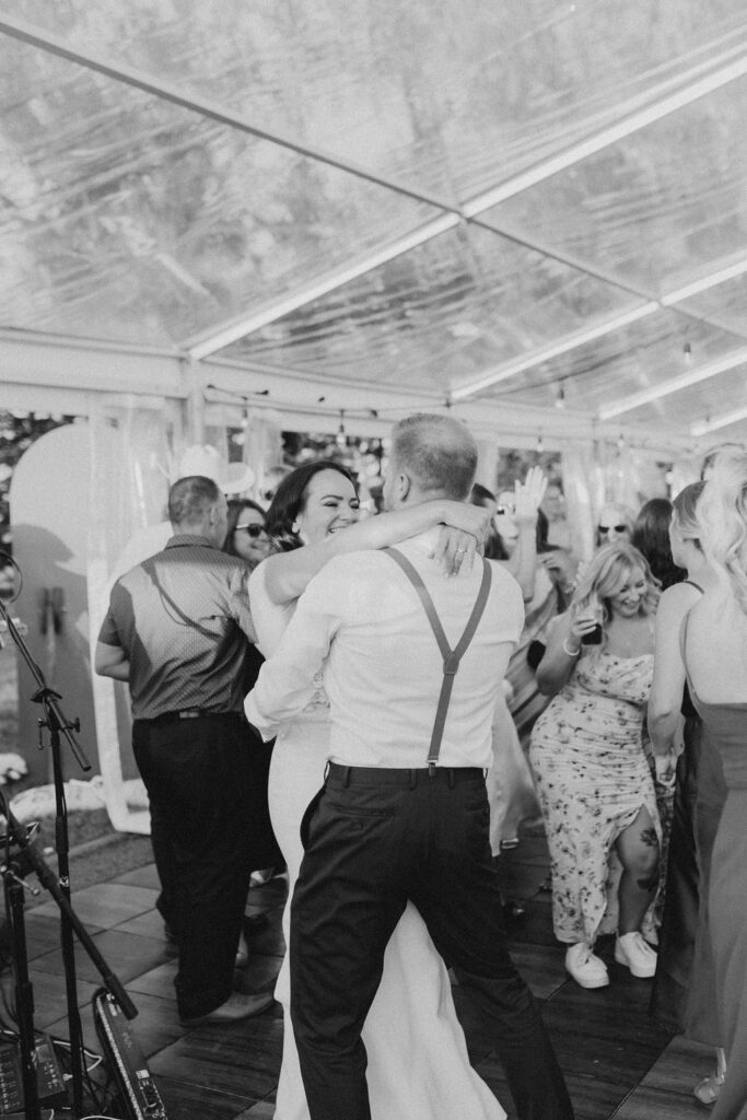 A bride and groom dancing in a tent.