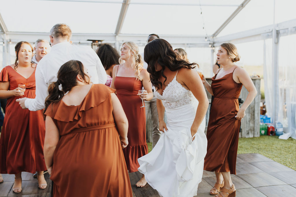 A group of bridesmaids dancing in a tent.
