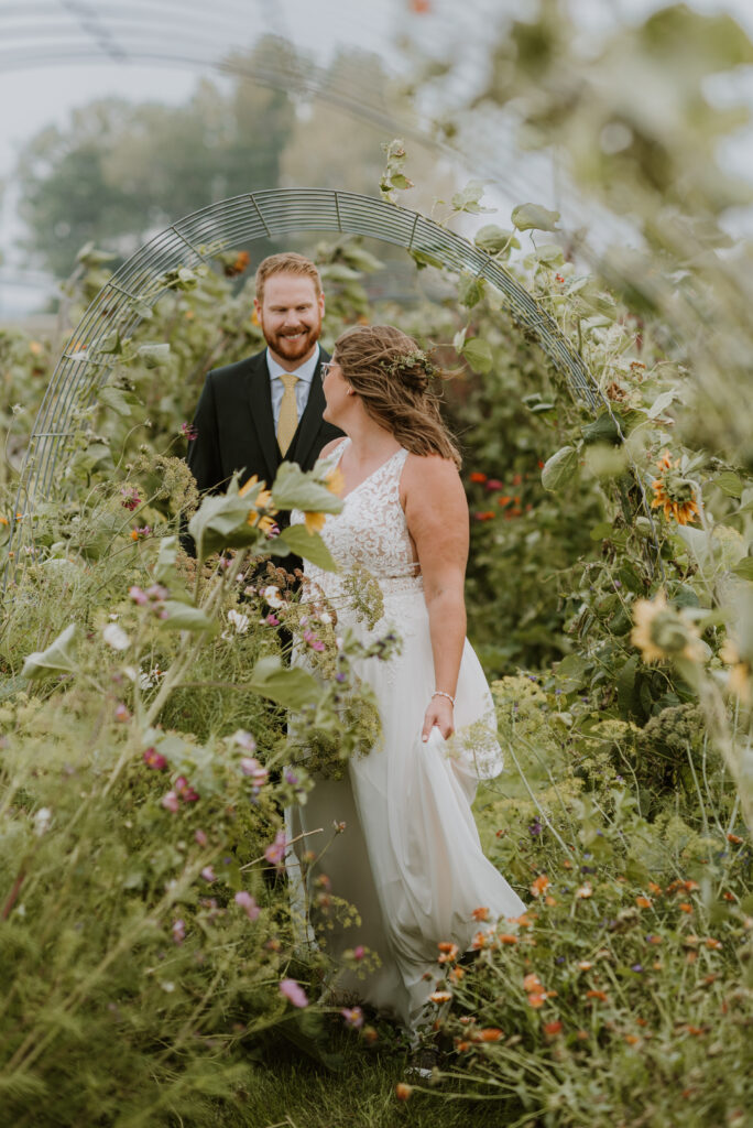 A bride and groom walk through a garden at their wedding.