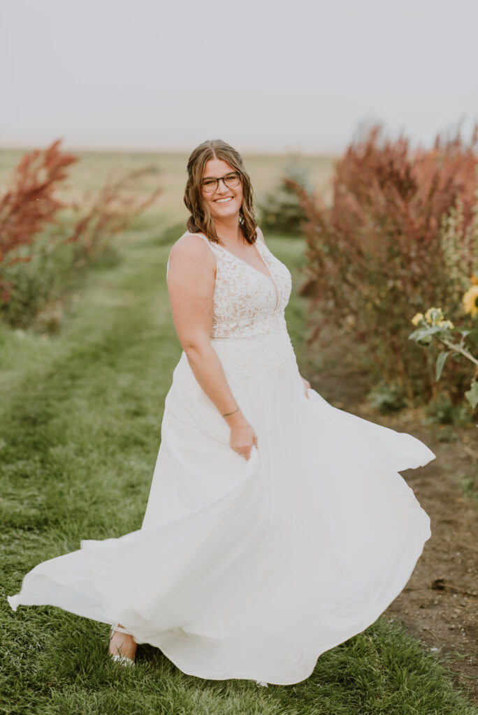 A bride in a white wedding dress standing in a field of sunflowers.