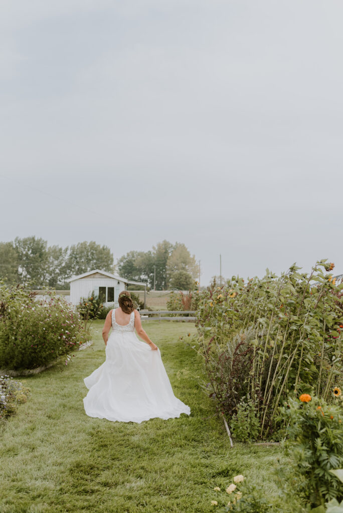 A bride walking through a garden in her wedding dress.