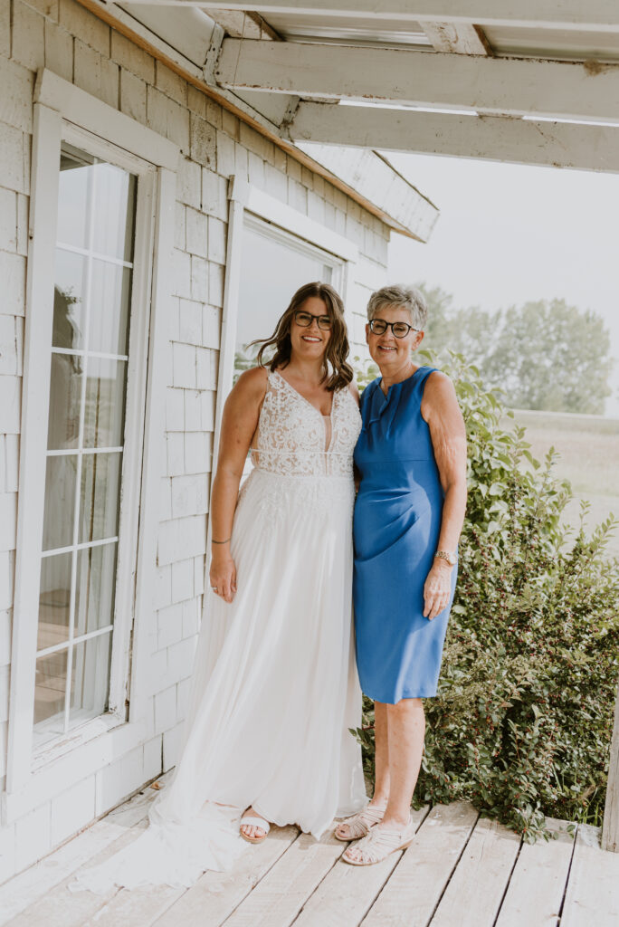 A bride and her mother standing on a porch.