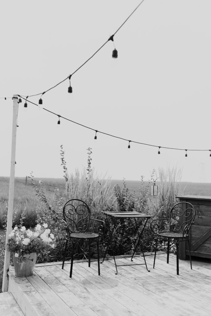 A black and white photo of a deck with string lights.