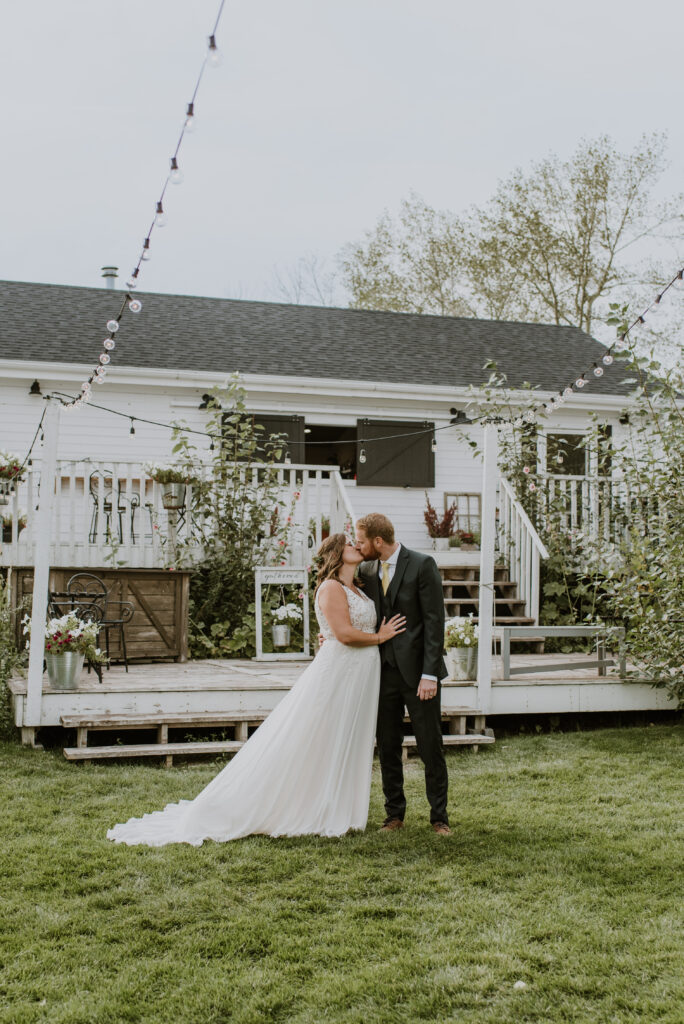 A bride and groom kissing in front of their home.