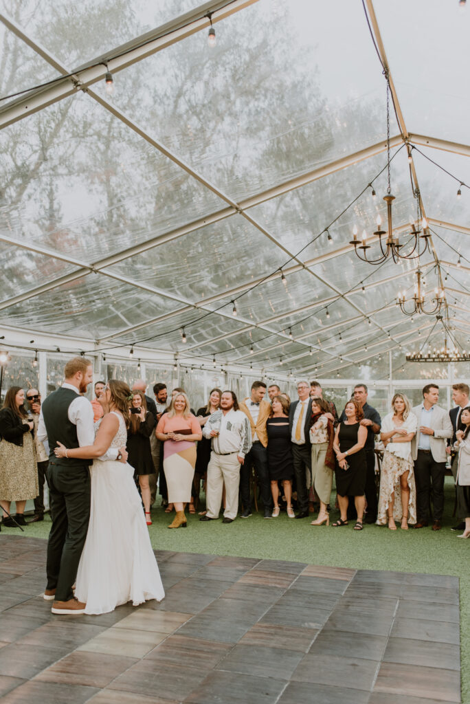 A bride and groom sharing their first dance in a tent.