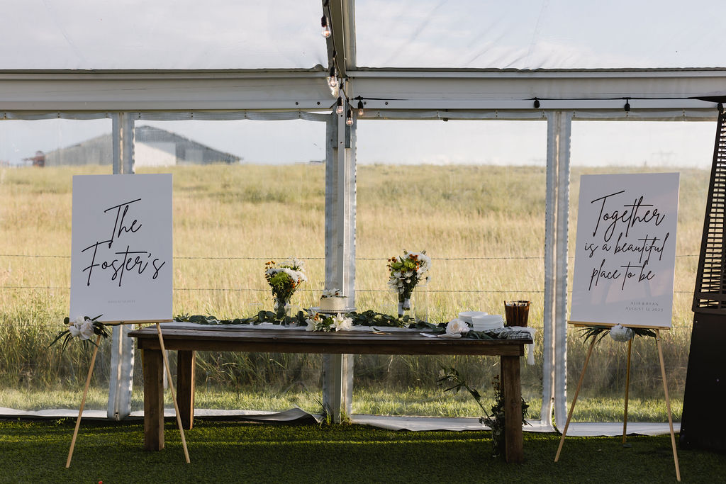 A table with two signs in front of a tent. diy florals