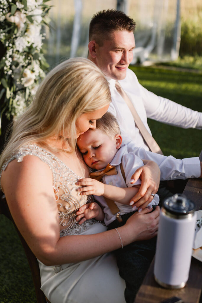 A man and woman holding a baby at an outdoor wedding.