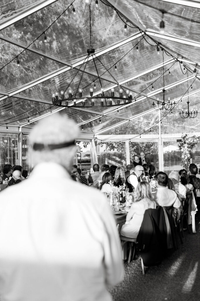 A black and white photo of a wedding reception in a tent.