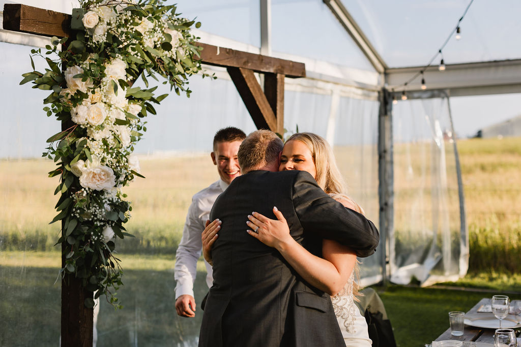A bride and groom hugging in front of a tent.