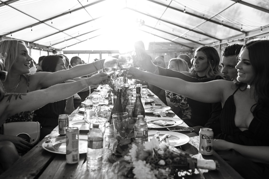 A group of people toasting at a table in a tent.