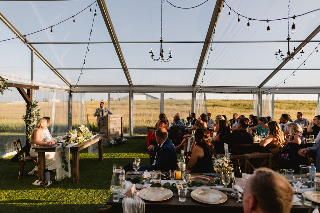 A wedding reception in a tent with tables and chairs.