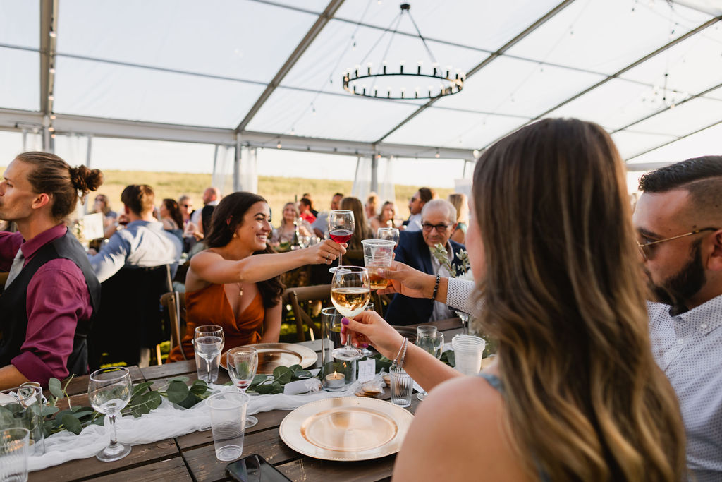A group of people toasting at a wedding reception in a tent.