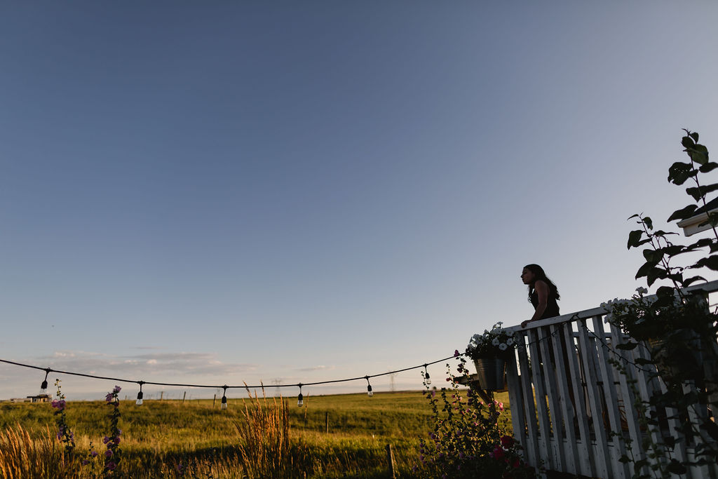 A bride standing on a balcony overlooking a field.