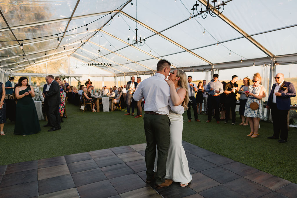 A bride and groom sharing their first dance in a tent.