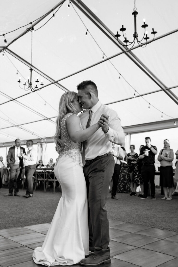 A bride and groom sharing their first dance under a tent.