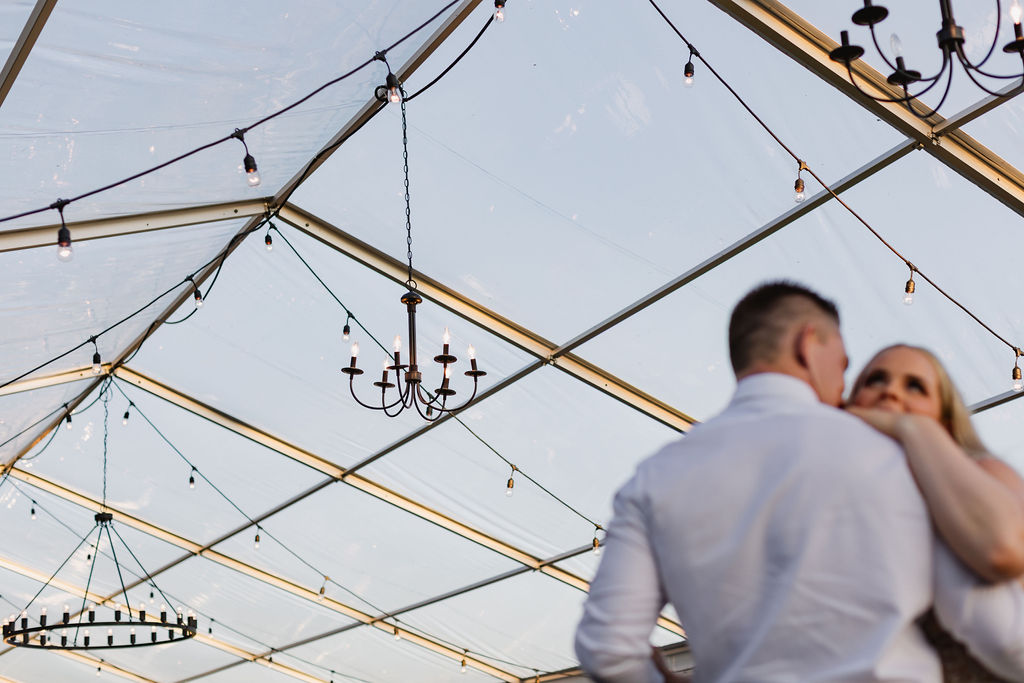 A bride and groom hugging under a tent.