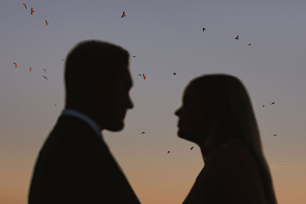 A silhouette of a couple looking at each other at sunset.