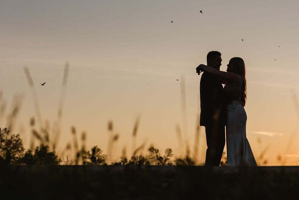 A silhouette of a bride and groom at sunset.