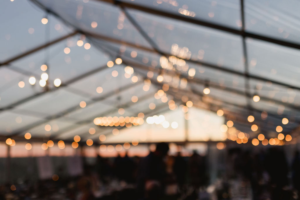 A wedding reception in a clear tent at dusk.