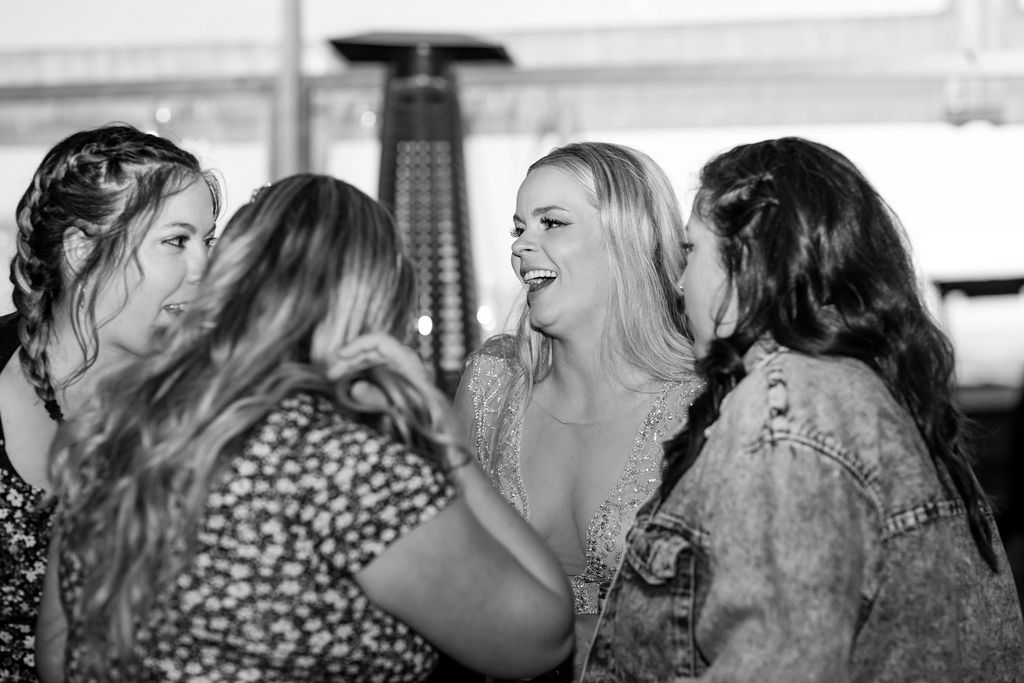 A group of women laughing at each other in a black and white photo.