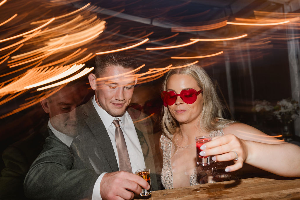 A bride and groom holding glasses at a party.