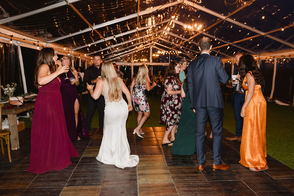 A group of people dancing in a tent at a wedding.