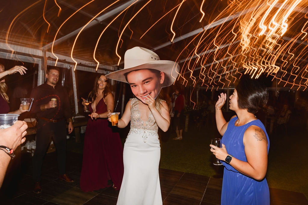 A bride wearing a cowboy hat at a wedding reception.
