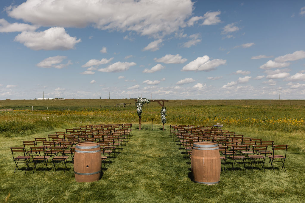 A wedding ceremony set up in a field with barrels.