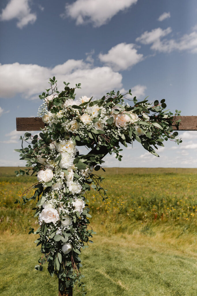 A flower arrangement on a wooden cross.