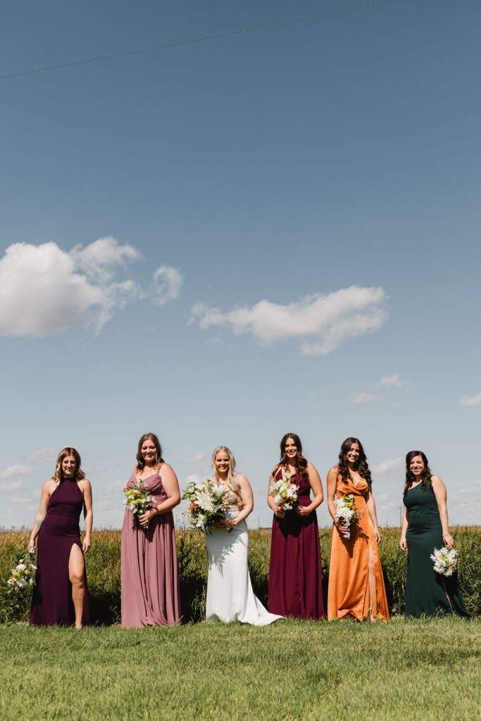 A group of women in mix matched colorful dresses holding DIY wedding floral bouquets