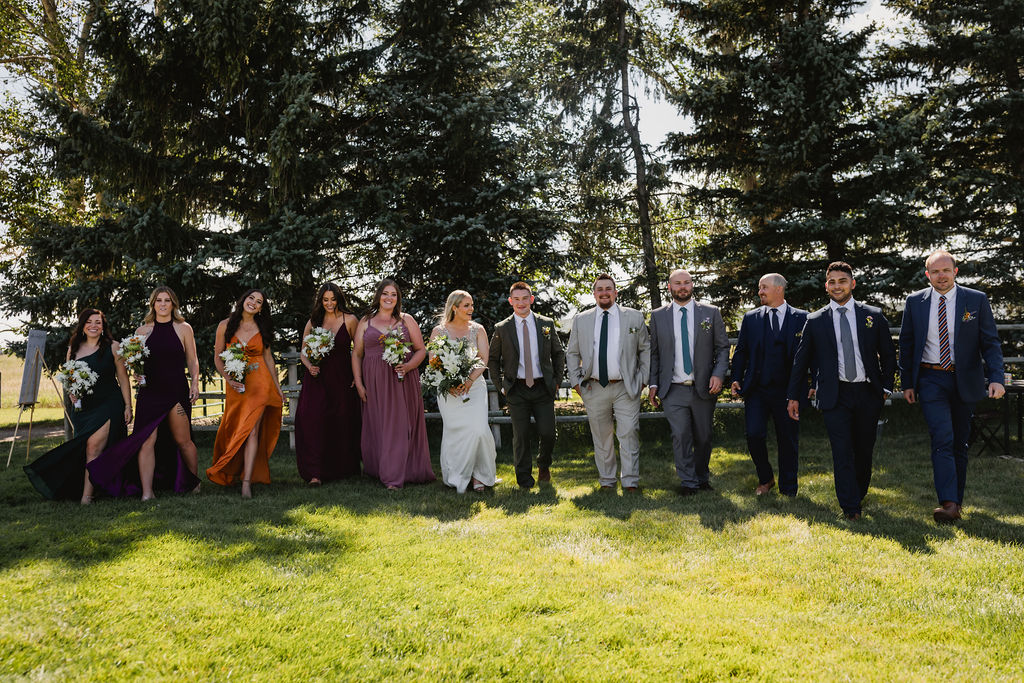 A group of bridesmaids and groomsmen standing in front of a tree.