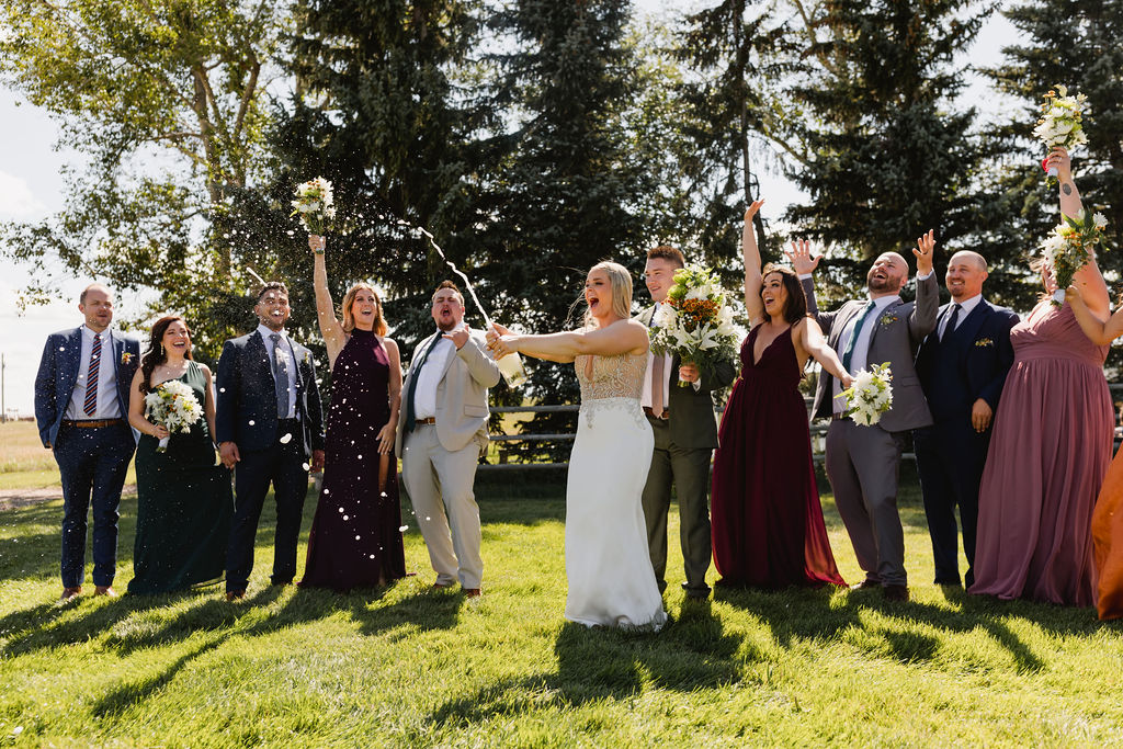 A group of bridesmaids and groomsmen throwing confetti at each other.