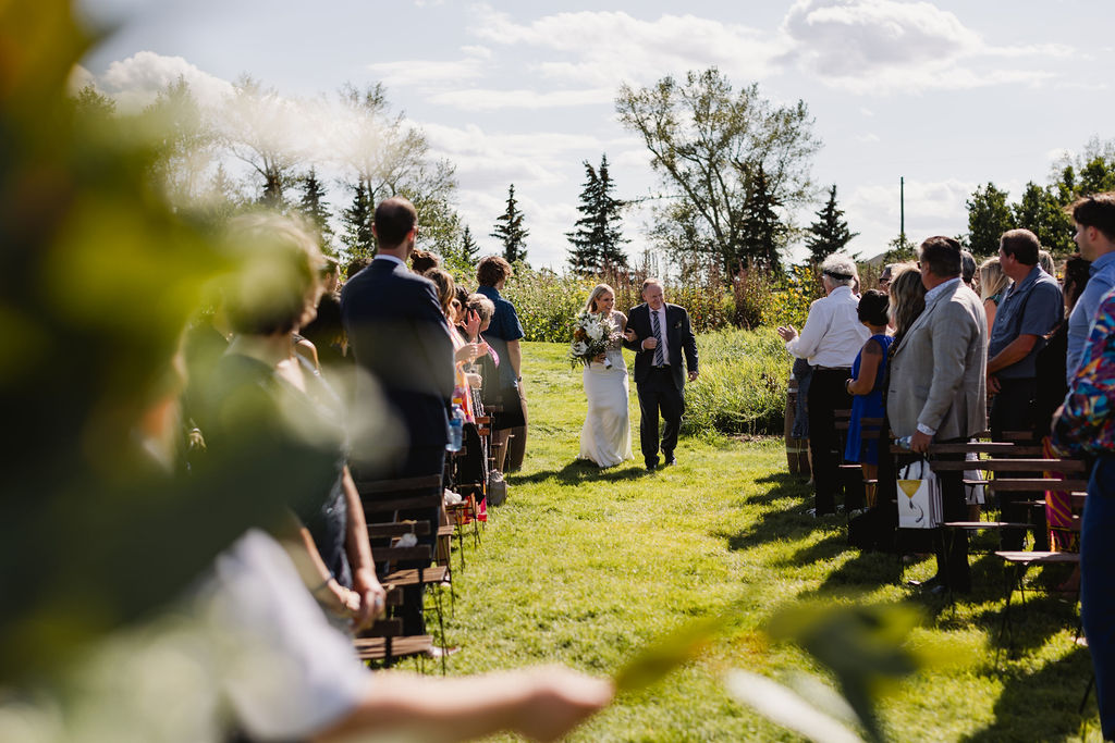 A bride and groom walking down the aisle at an outdoor wedding.