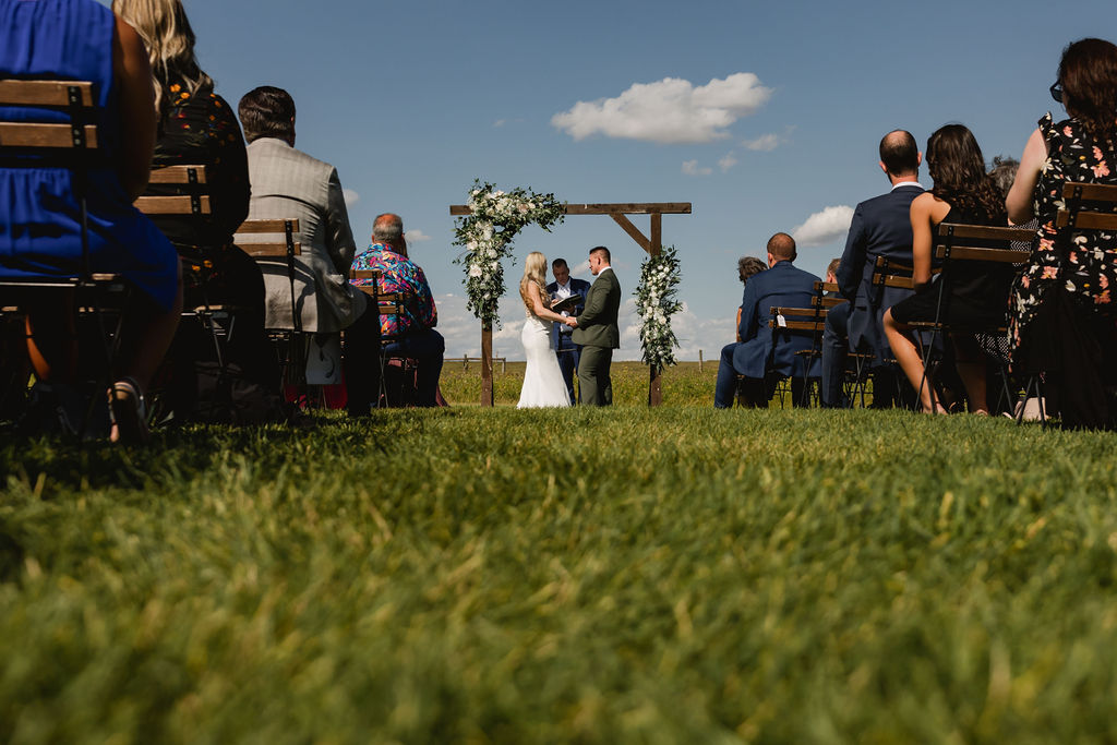 A bride and groom standing in the grass at their wedding ceremony.