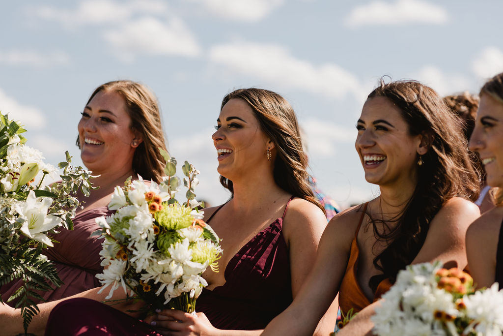 A group of bridesmaids laughing while holding bouquets.