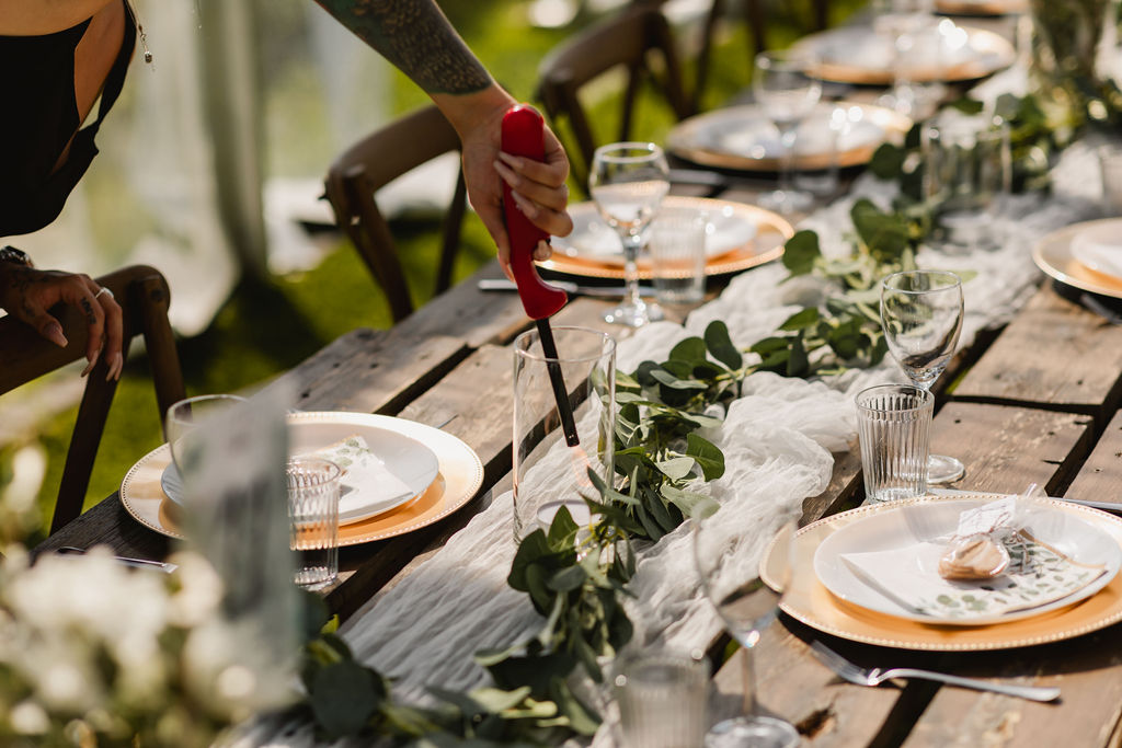 A woman is setting a table at an outdoor wedding.