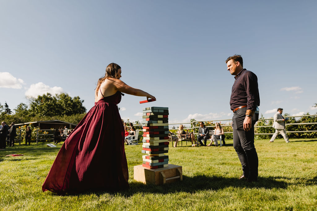 A bride and groom playing a game of jenga in the grass.