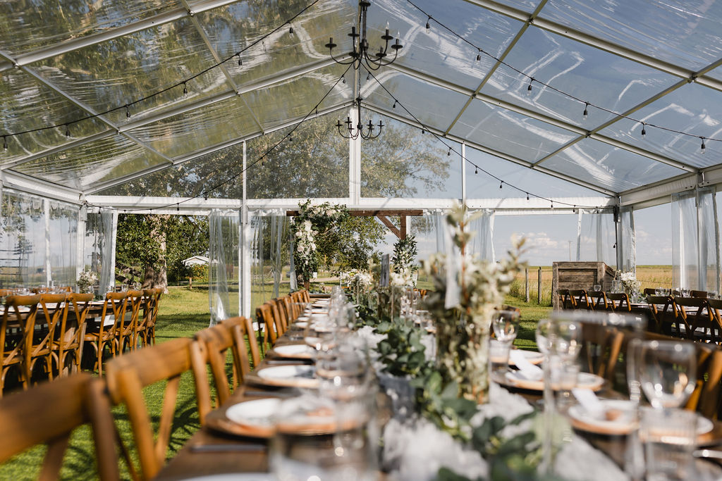 A wedding reception set up in a clear tent with DIY florals 