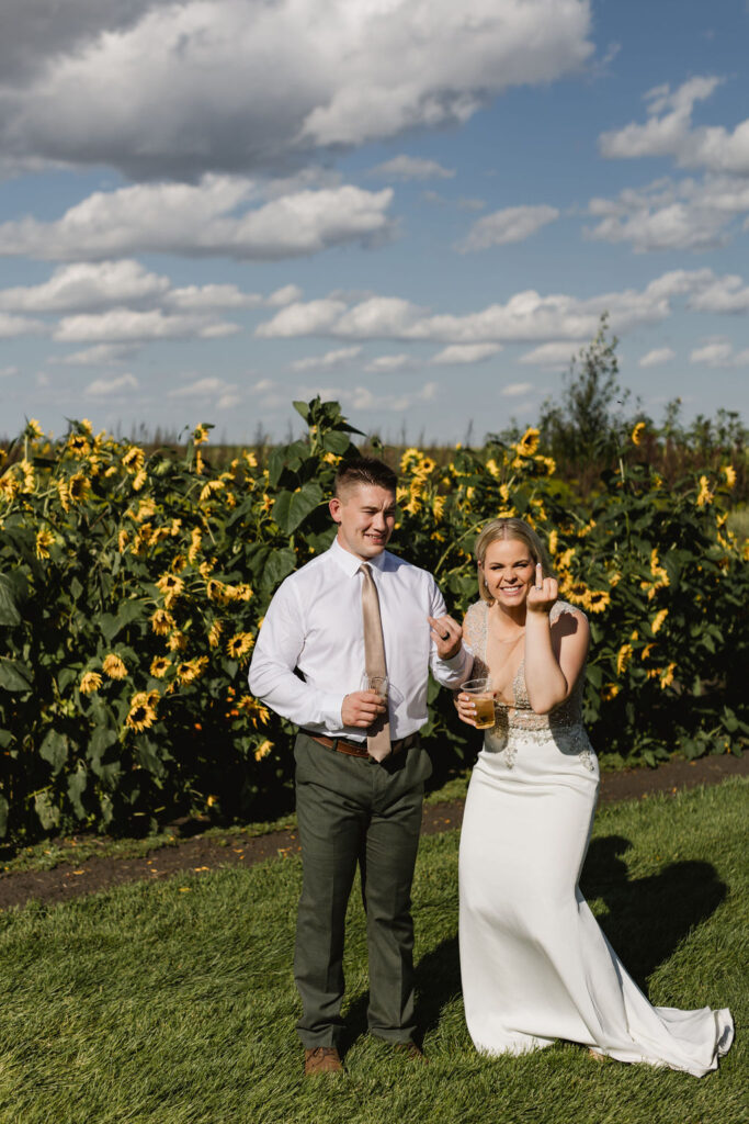 A bride and groom standing in front of sunflowers.