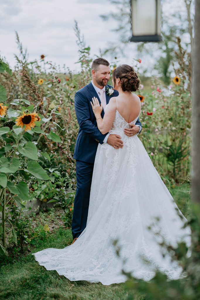 Bride and groom sharing an intimate moment amidst a garden with sunflowers.