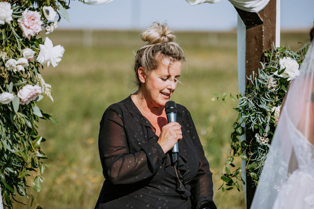 Woman giving a speech at an outdoor wedding ceremony.