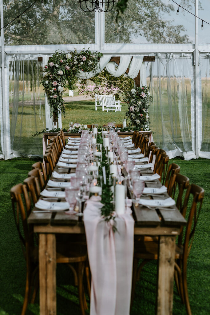 Elegantly set dining table for a garden wedding reception with floral decorations.