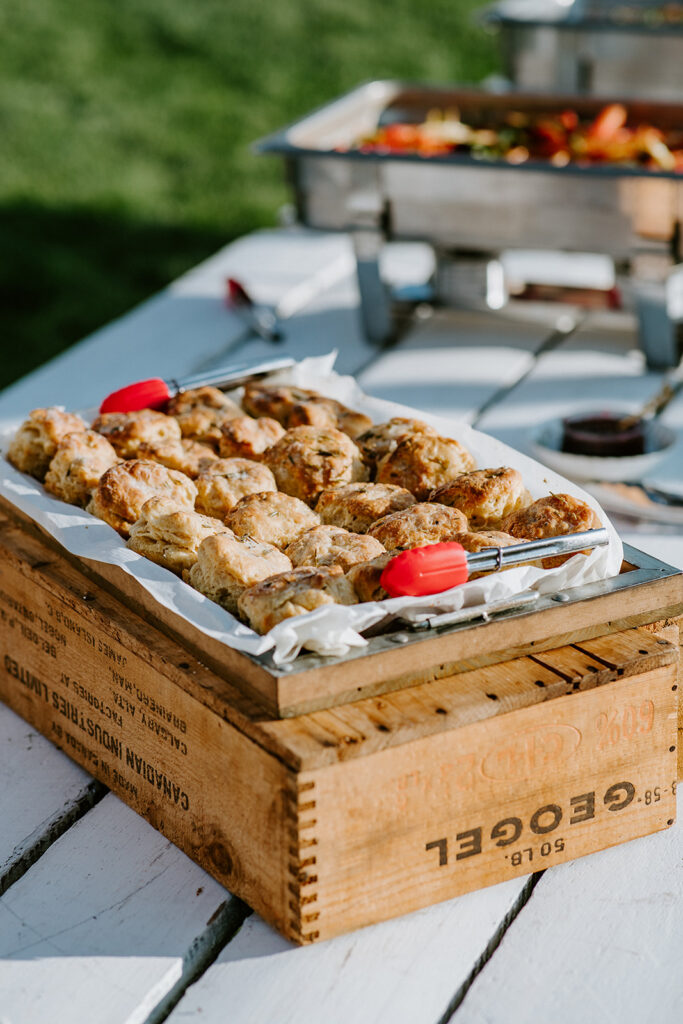 Grilled chicken pieces served on a wooden crate at an outdoor event.