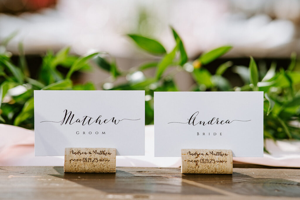 Place cards labeled "matthew groom" and "andrea bride" with cursive writing on a table.