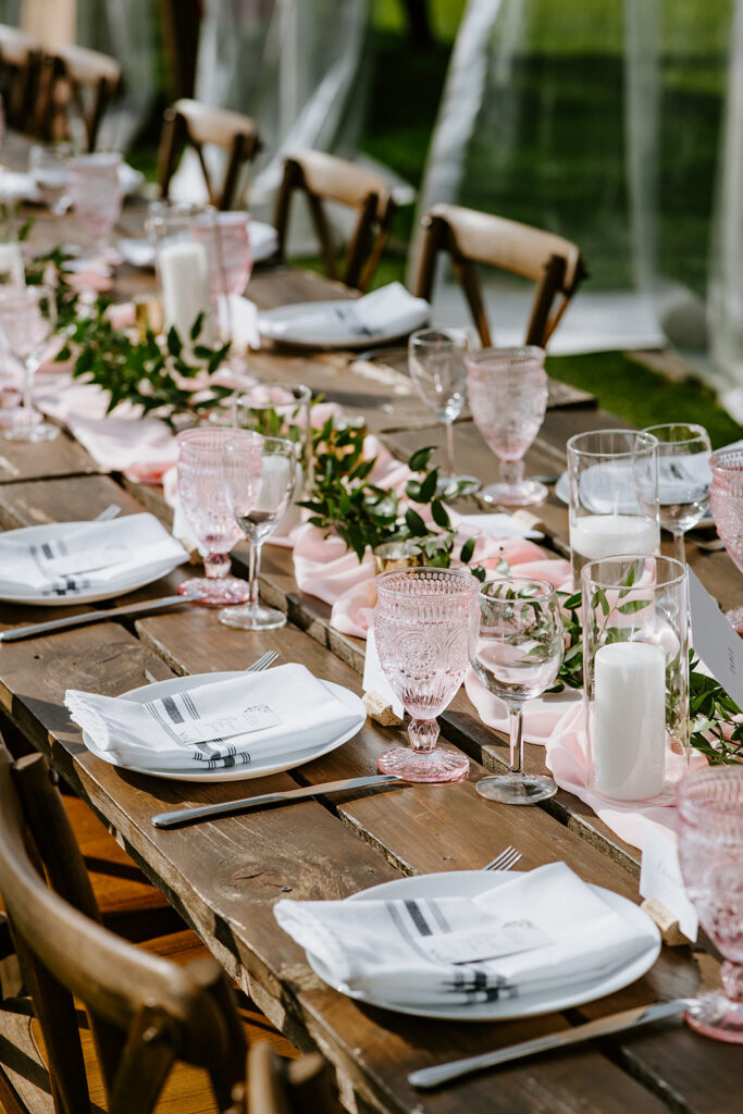 An elegantly set outdoor dining table with floral decorations and pink glassware.