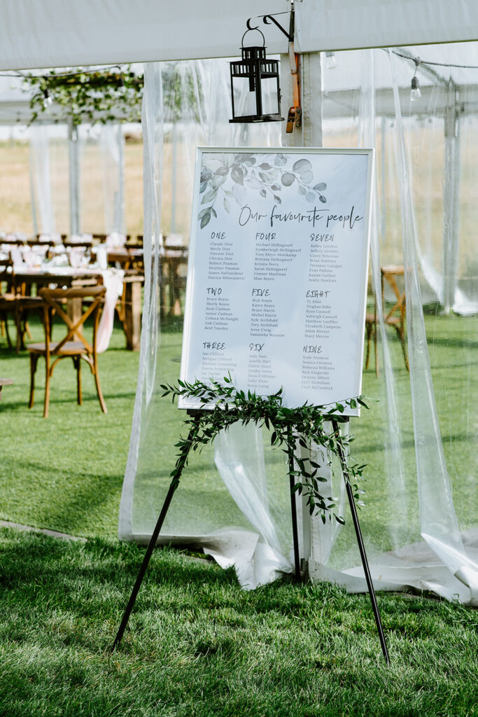 Elegant seating chart displayed on an easel at an outdoor wedding venue.
