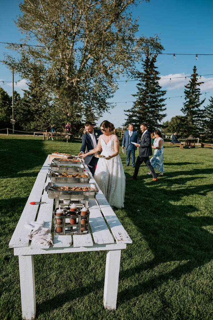 A bride and groom playing a giant beer pong game at an outdoor wedding reception.