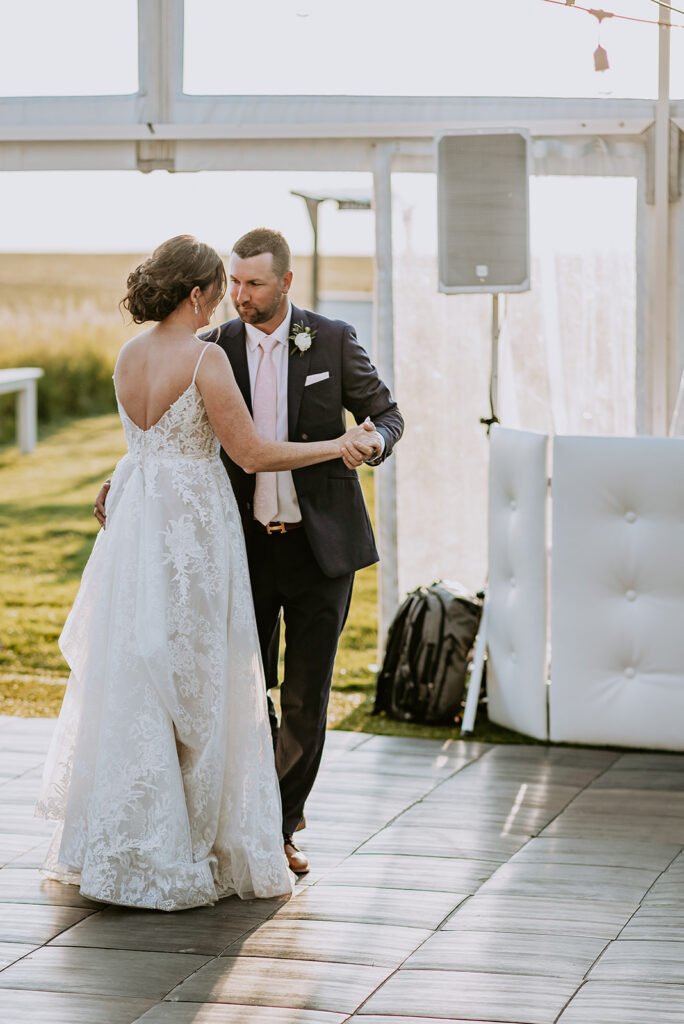 A bride and groom share a dance outdoors with a speaker system in the background.