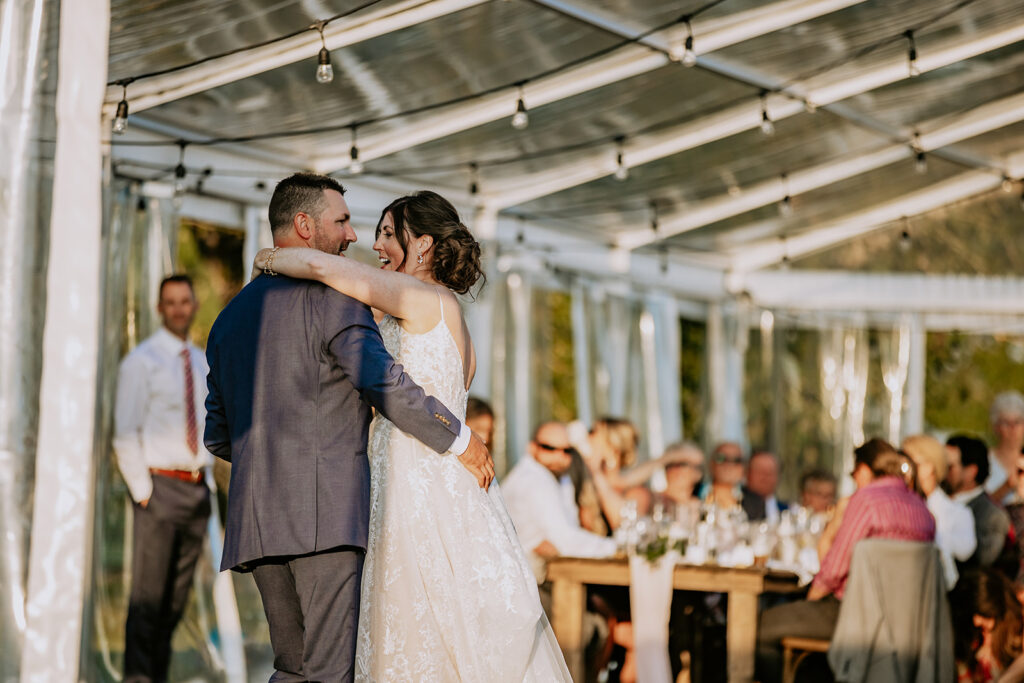 A newlywed couple sharing a dance at their outdoor wedding reception.